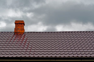 brown roof with red chimney against cloudy skies